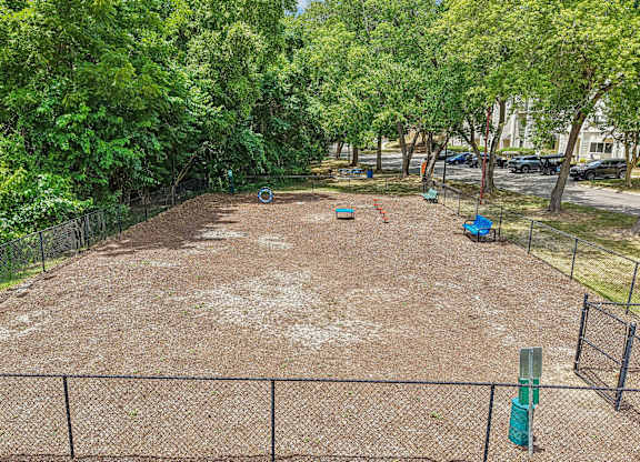 A tennis court surrounded by a fence and trees.