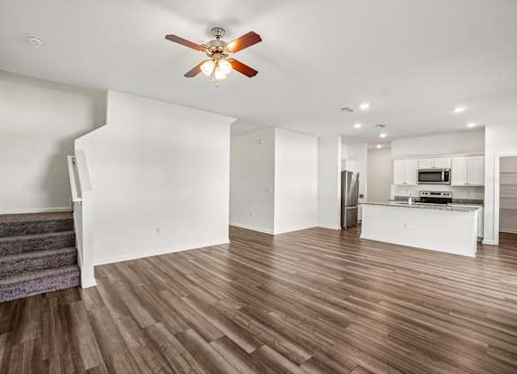 A living room with a staircase and a ceiling fan.
