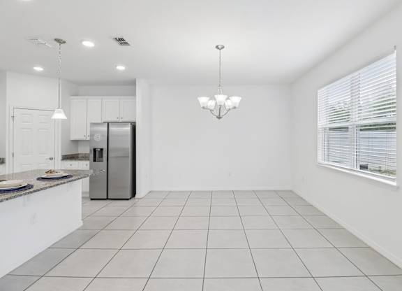 A kitchen with white cabinets and a refrigerator.
