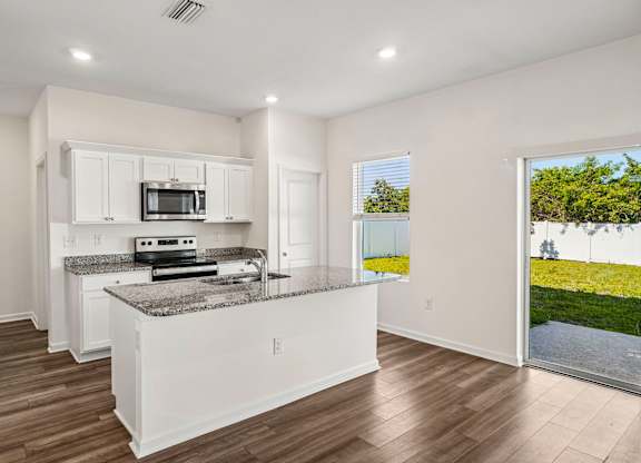 A kitchen with white cabinets and a granite countertop.