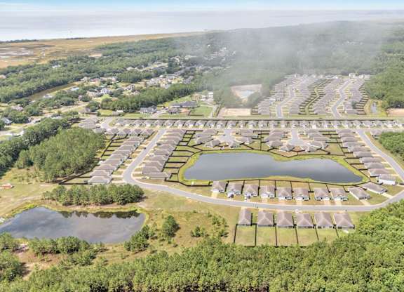 A bird's eye view of a residential area with a lake in the middle.