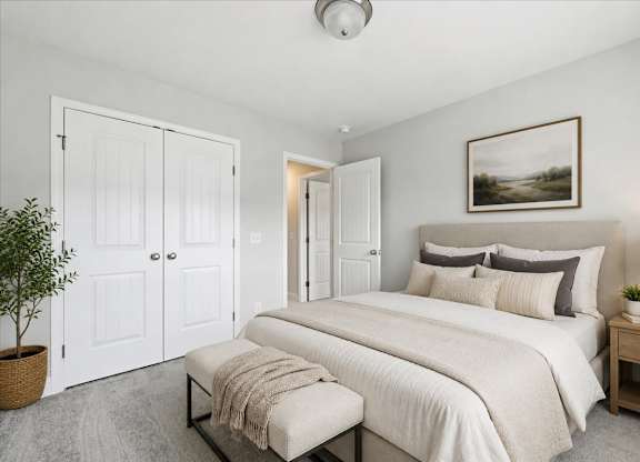 A bedroom with a large bed, a bench, and a potted plant.