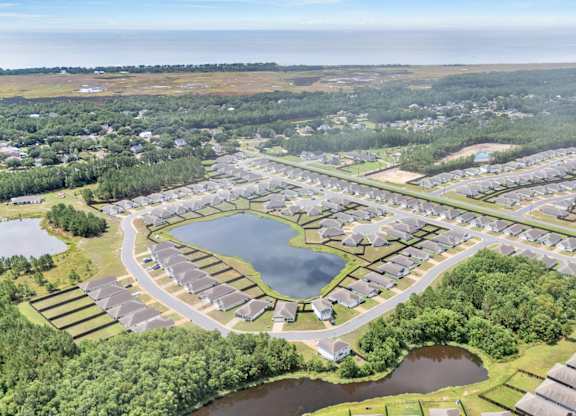 A bird's eye view of a residential area with houses, roads, and a lake.