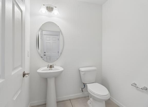 A white bathroom with a toilet, sink, and mirror.