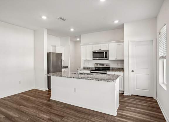 A kitchen with white cabinets and a granite countertop.