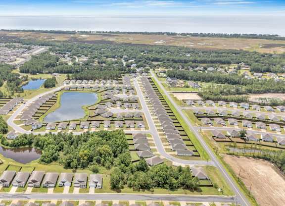 A bird's eye view of a residential area with a lake and a river in the background.
