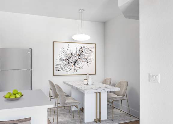 A modern kitchen with a white marble table and chairs.