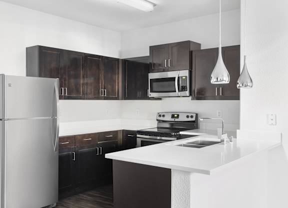 A modern kitchen with a refrigerator, microwave, oven, and cabinets.