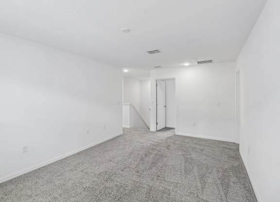 A spacious room with a carpeted floor and white walls.