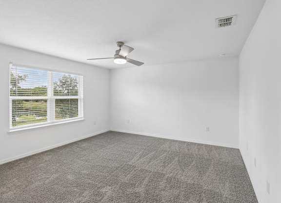A room with a ceiling fan and carpeted floor.