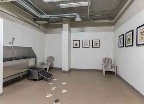 A room with a fridge, two chairs and pictures on the wall.