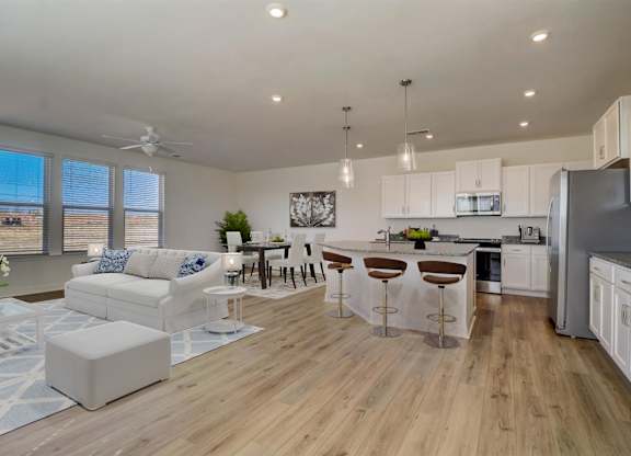 A modern kitchen with white cabinets and a wooden floor.