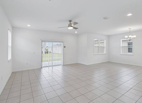 A spacious room with a ceiling fan and sliding glass doors.