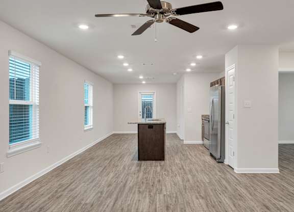 A spacious room with a ceiling fan and wooden flooring.