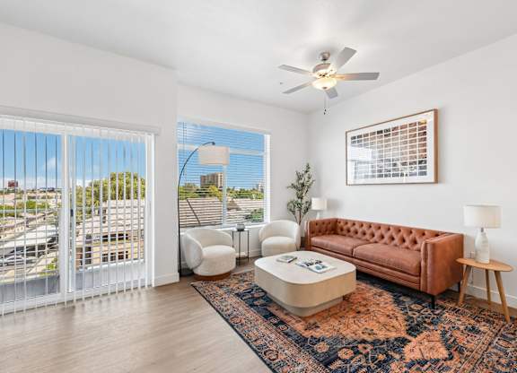 A living room with a brown couch and a ceiling fan.