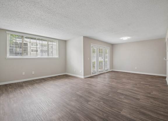 A room with wooden flooring and a window with blinds.