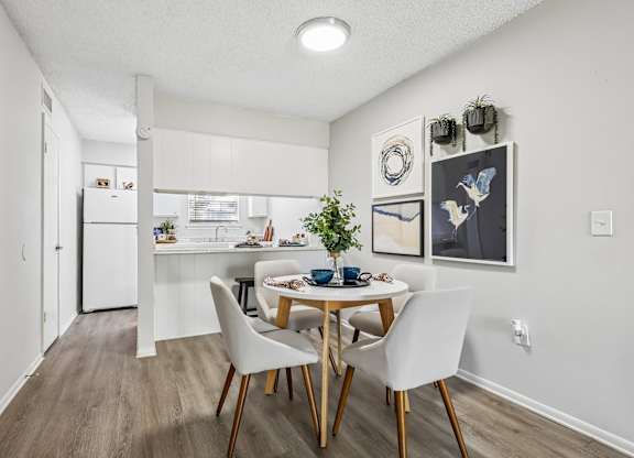 A dining room with a table set for two and a kitchen in the background.