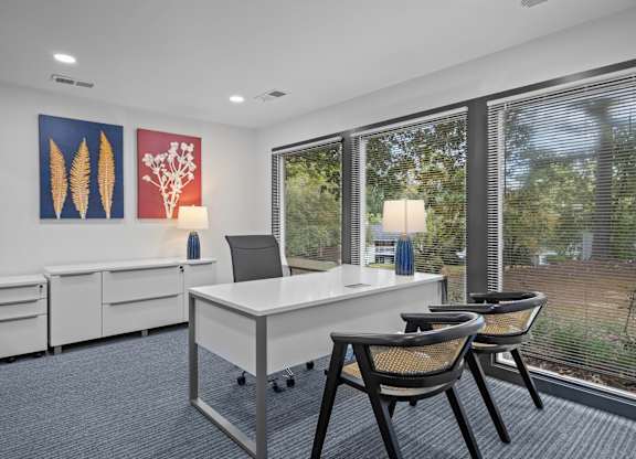 A white desk with two chairs and a laptop on it.