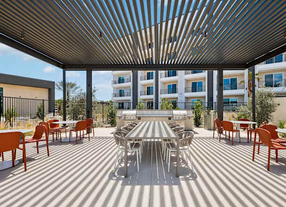 A patio with a table and chairs is covered by a striped awning.