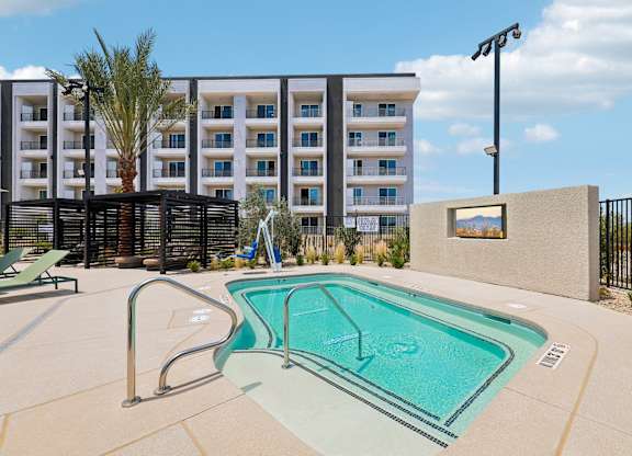 A small pool in front of a building with a palm tree.