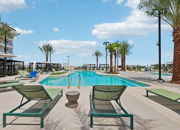 A pool area with sun loungers and palm trees.