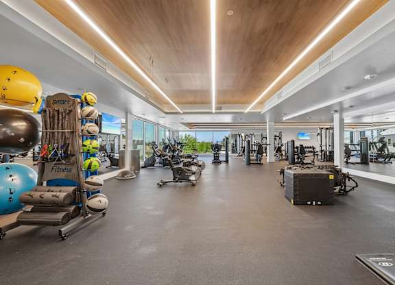 A gym with a variety of equipment and a large mirror on the wall.