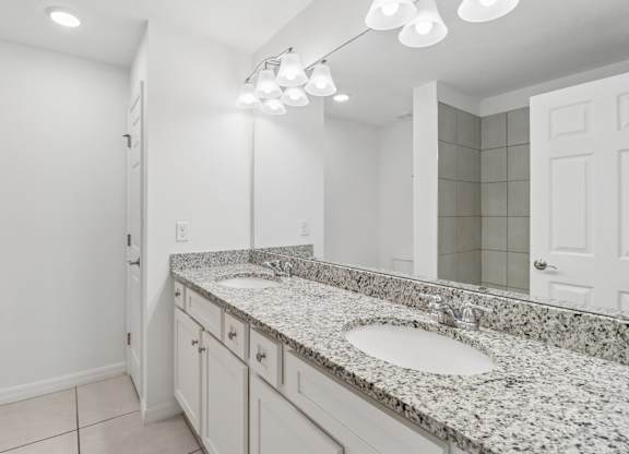 A bathroom with granite countertops and a large mirror.