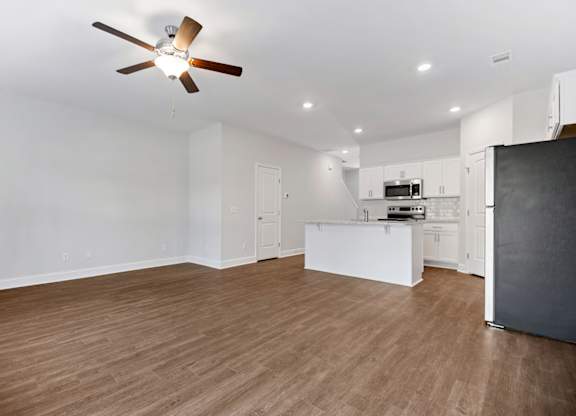 an empty living room and kitchen with a ceiling fan