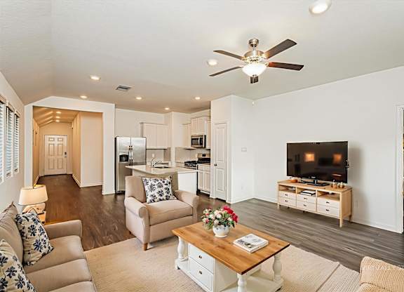 A living room with a couch, a coffee table, and a television.