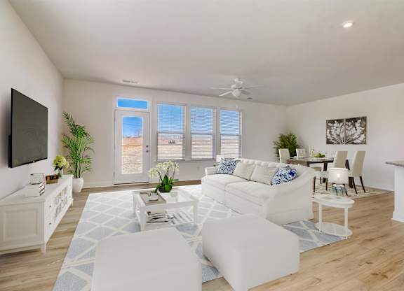 A living room with white furniture and a flat screen TV mounted on the wall.