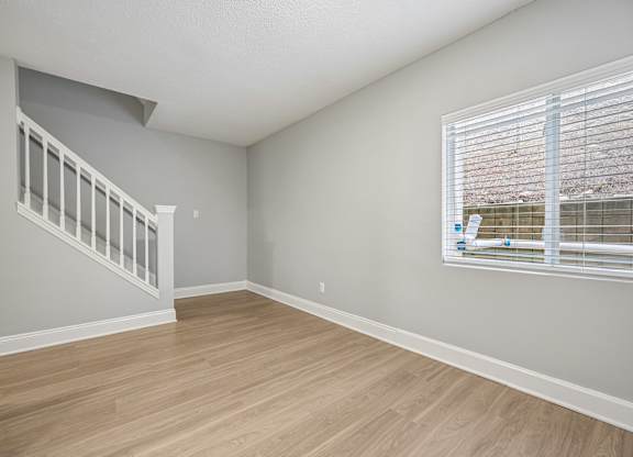 A room with a staircase and a window with blinds.