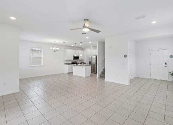 A spacious white room with a ceiling fan and tiled flooring.