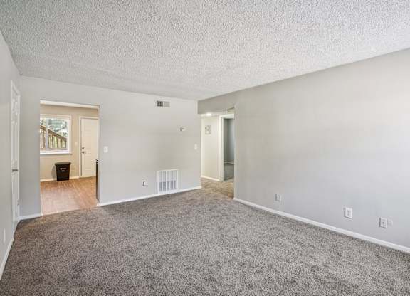 A spacious room with carpeted floor and white walls.