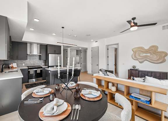 A modern kitchen with a dining table set for two.