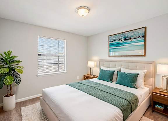 A bedroom with a large bed and a potted plant.