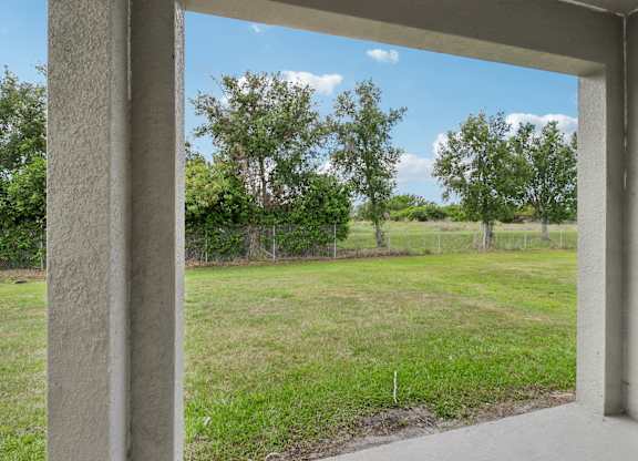 A view from a covered porch looking out to a grassy field.