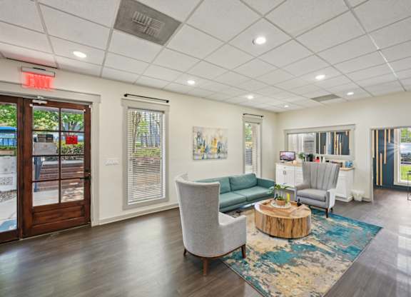 Modern office waiting area with teal sofa, gray chairs, and wood coffee table.