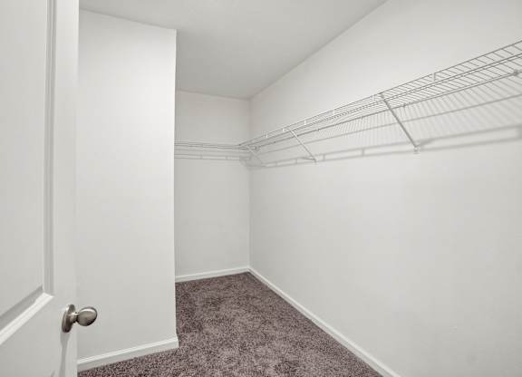 A white door is open to a room with a carpeted floor and a wire shelving unit.