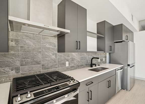 A modern kitchen with a stove, sink, and refrigerator.