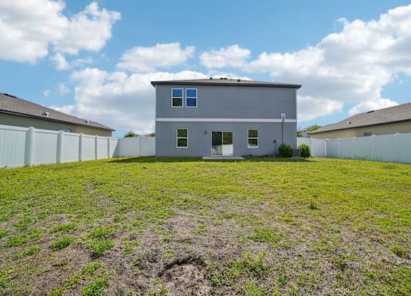 A grey house with a white fence in front of it.