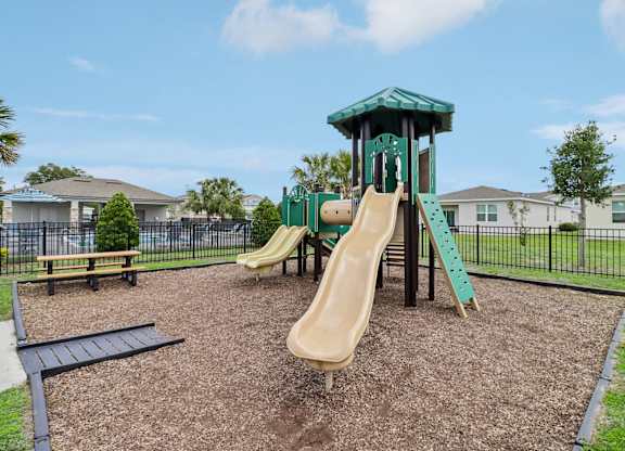 A playground with a green slide and a wooden slide.