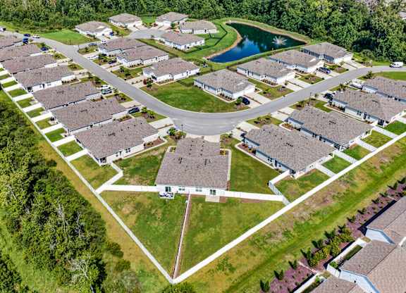 A bird's eye view of a residential area with houses and a pond.