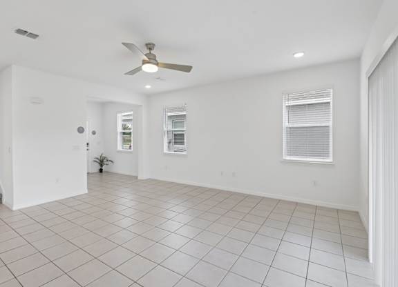 A spacious room with a ceiling fan and tiled flooring.