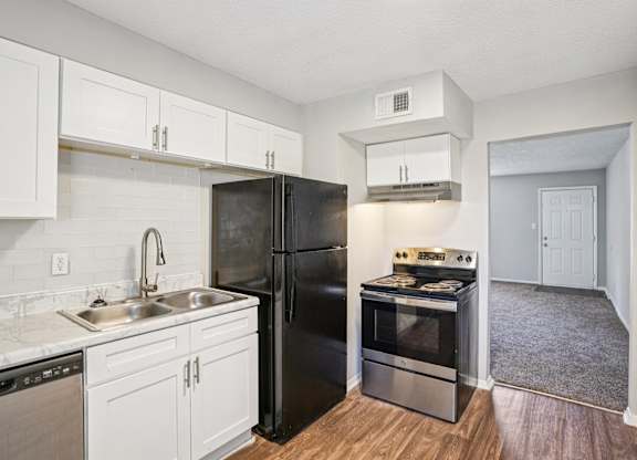 A kitchen with black appliances and white cabinets.