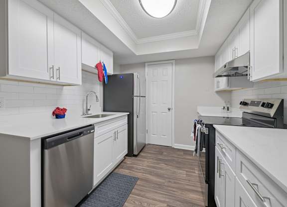 A kitchen with white cabinets and a stainless steel dishwasher.
