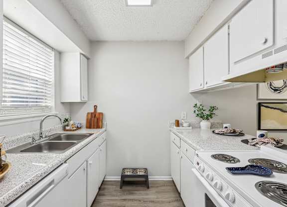 A kitchen with white cabinets and a white stove top oven.