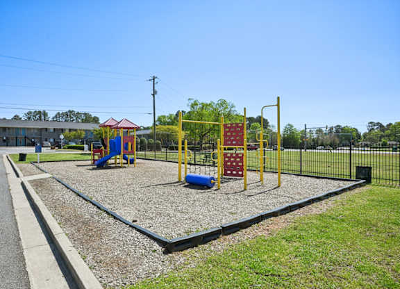 Outdoor playground with slide, climbing structures, and wood chip ground cover.