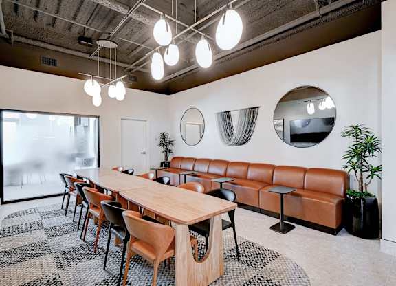 A conference room with a long table, chairs, and mirrors on the wall.