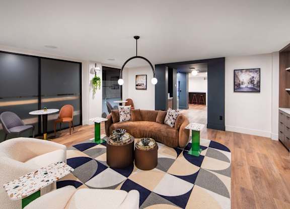 A modern living room with a black and white rug and a variety of seating options.
