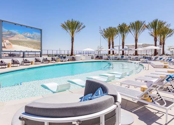 A large screen is mounted on a wall above a pool.